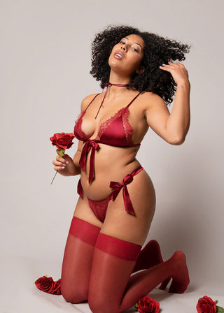 Elegant photo of curvy woman in burgundy lingerie set holding a rose and looking beautiful and confident. 