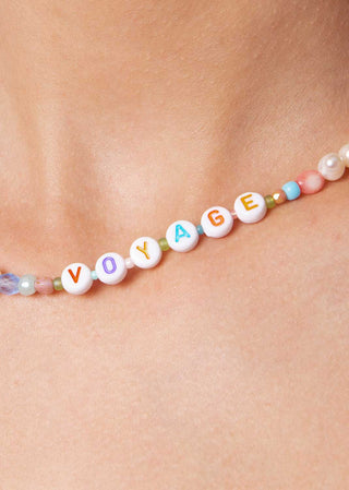 detail of playful necklace with colorful beads and word "voyage" from lioa lingerie