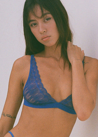 Woman wears blue lingerie with geometric details. The bralettet has wider cups for a good fit for larger cup sizes. This lingerie is designed in Switzerland and made in Portugal.