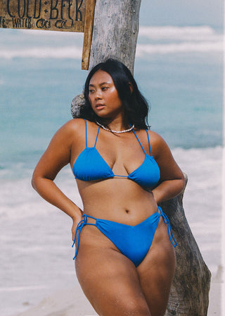 Woman wears a bright blue bikini top. The bikini is a classic triangle with double strap details. This is a sustainable swimwear piece and is from Lioa Lingerie, a Swiss Swimwear Brand.