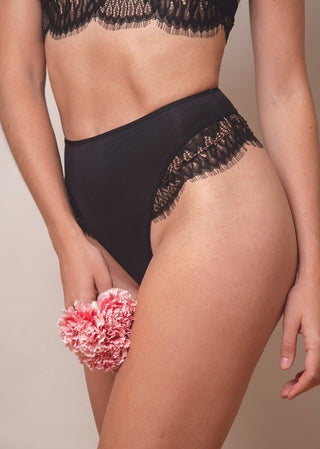 Woman wears a high-waist thong with lace details at the side and comfortable jersey. The black lingerie is from Lioa Lingerie, a Swiss Lingerie Brand.